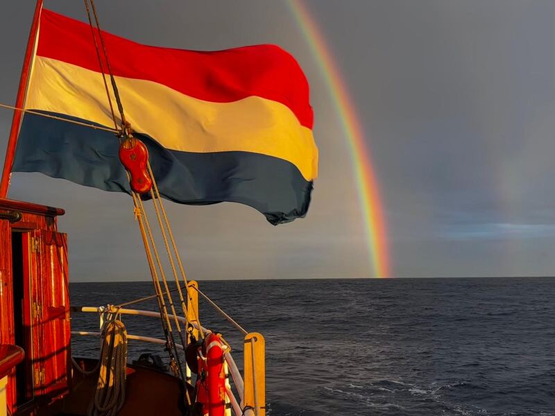 Dutch ensign and a rainbow, at sea