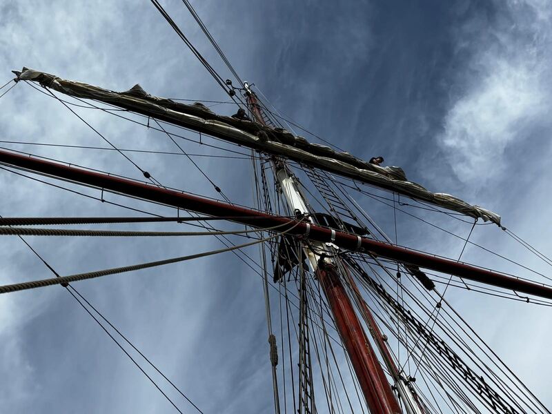 Up the foremast, square sails furled, crew on the yard