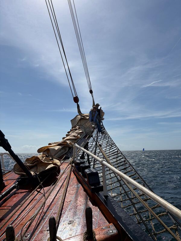 Out on the bowsprit, a yacht on the horizon