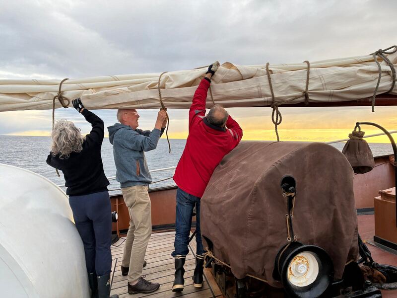 Stowing the sail at sunset, three of the voyage crew
